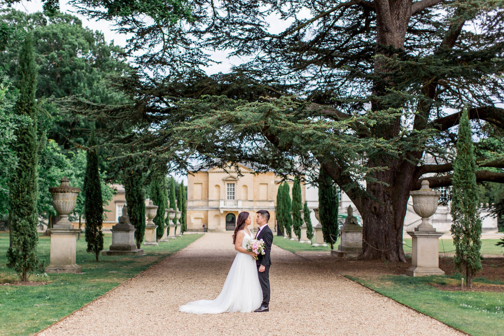 Bride and Groom standing in the distance with large trees around them